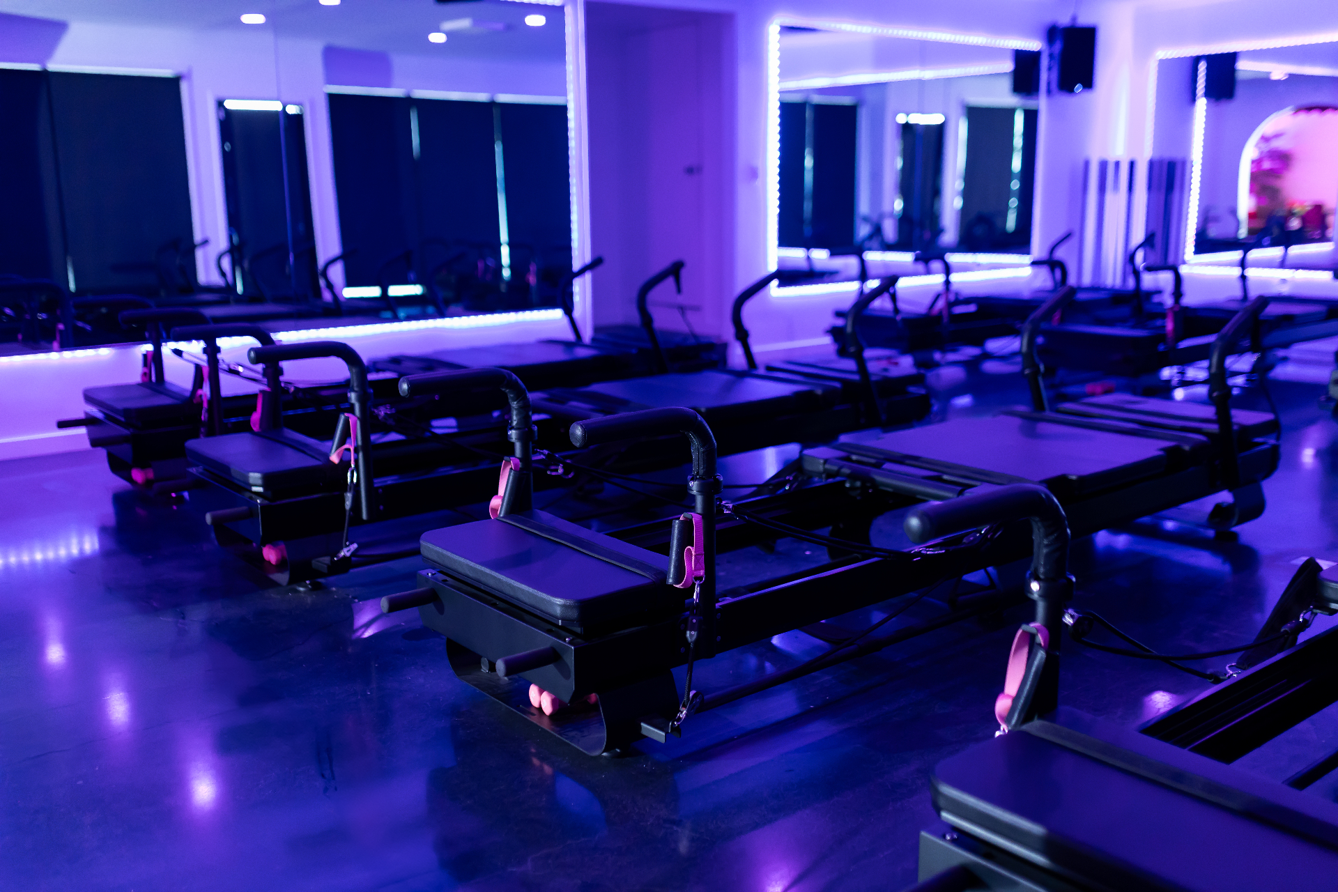 Rows of Pilates X-Former reformers lit by purple LEDs inside the DollHouse studio